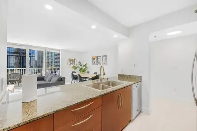 a kitchen with a sink and a living room at Modern Brickell Condo with Prime City Views in Miami