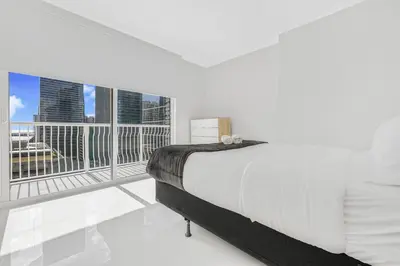 a white bedroom with a bed and a balcony at Modern Brickell Condo with Prime City Views in Miami