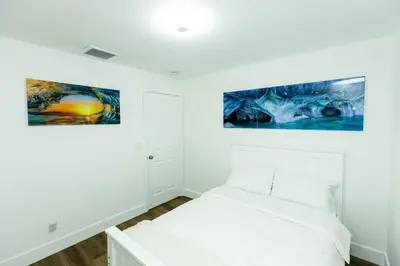 a white bedroom with two paintings on the wall at Your Perfect Oasis in Miami! in Miami