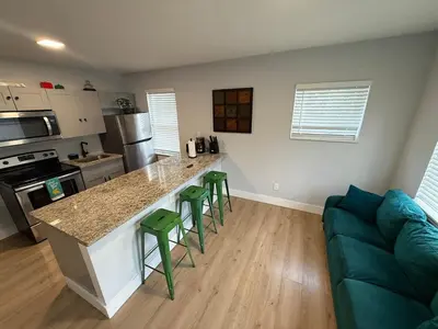 a kitchen with a counter and four green bar stools at Prime Location Near Wynwood in Miami