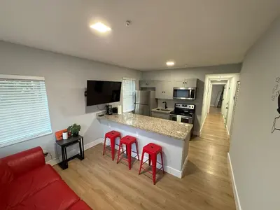 a living room with a kitchen and red stools at Perfect Central Stay in Miami