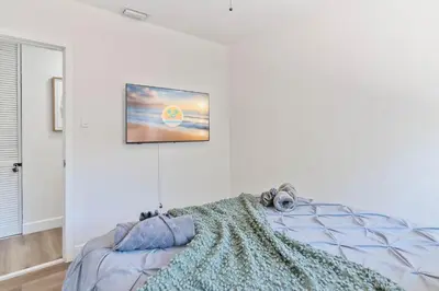 a bedroom with a tv hanging on the wall at Near Beach Family Escape Heated Pool Fire Pit BBQ in Hallandale Beach