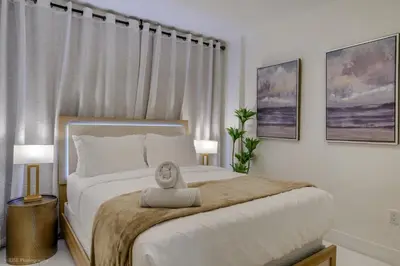a bedroom with a large white bed with two lamps at Beachfront Oasis in Sunny Isles 3BR, Pool & Tennis in Sunny Isles Beach