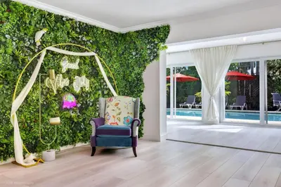 a room with a blue chair in front of a ivy covered wall at Tropical 3BR Escape with Pool, 7 Min Drive to Beach in Hollywood