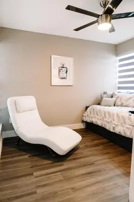 a bedroom with a white chair in front of a bed at Welcome to 305 Rentals in Miami Gardens