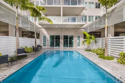 a swimming pool in front of a building with palm trees at Resort-Style 1 Bed Condo with Pool Parking Rooftop & Gym in Hollywood
