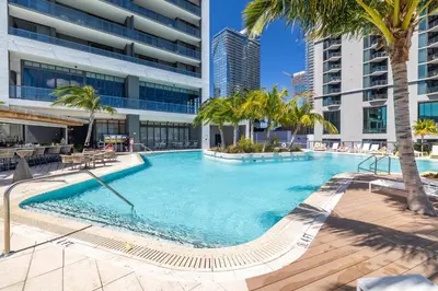 a large swimming pool with palm trees and buildings at Phenomenal 1 Bed - Amazing views in Miami
