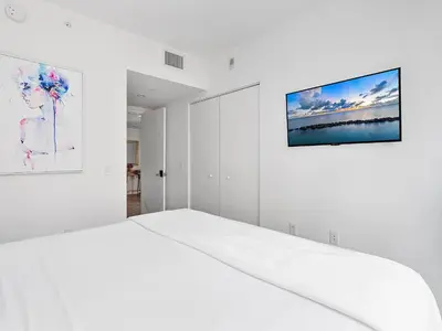 a white bedroom with a bed and a tv on the wall at X Lounge III-Modern Corner Residence in Miami