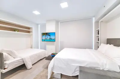 a white bedroom with two beds and a window at Great Miami Stay Steps from Bayside & the Beach in Miami