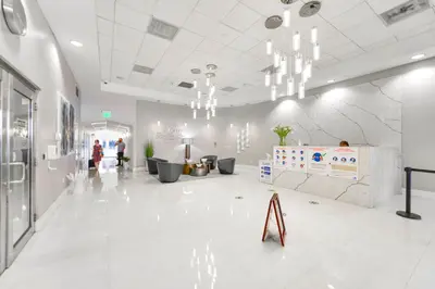 a lobby with white tile floors and chandeliers at Condo That Will Make Feel the Ocean Breeze Close in Miami