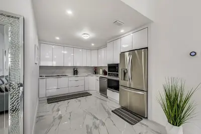 a kitchen with white cabinets and a stainless steel refrigerator at Luxurious Tropical Private Oasis by Mia Airport in Hialeah