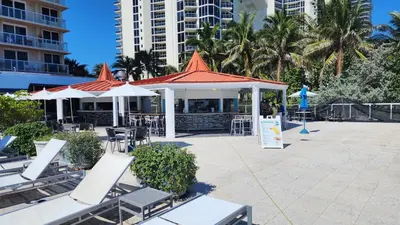 a restaurant with chairs and tables and umbrellas at Stunning Beachfront condo in sunny Sunny Isles Beach with AC, fitness room, WiFi in Sunny Isles Beach