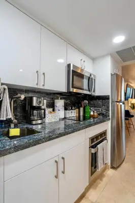 a kitchen with white cabinets and a stainless steel refrigerator at Stunning Beachfront condo in sunny Sunny Isles Beach with AC, fitness room, WiFi in Sunny Isles Beach