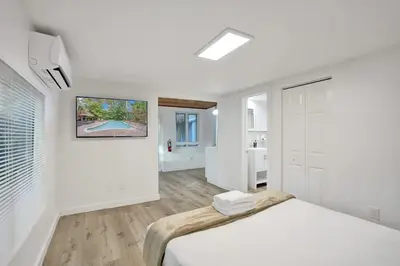 a white bedroom with a bed and a bathroom at Tropical Oasis Studio w Pool in Fort Lauderdale