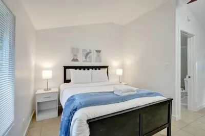 a white bedroom with a large bed with a blue blanket at Tropical Oasis Studio w Pool in Fort Lauderdale
