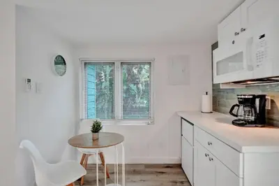 a white kitchen with a small table and white chairs at Tropical Oasis Studio w Pool in Fort Lauderdale