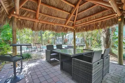 a patio with a table and chairs under a thatched roof at Tropical Oasis 2BR w Pool in Fort Lauderdale