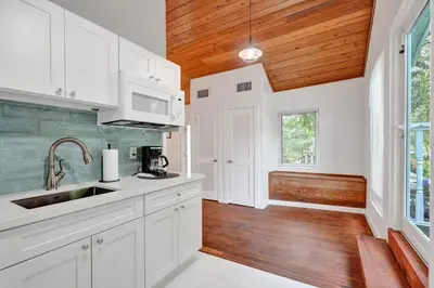 a kitchen with white cabinets and a wooden ceiling at Tropical Oasis Studio w Pool in Fort Lauderdale