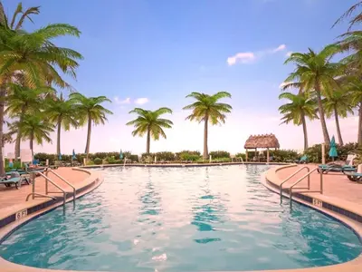 a swimming pool with palm trees in a resort at Stylish Ocean Apartment with Pool in Hollywood
