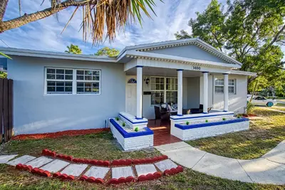 a white house with blue steps in front of it at Las Olas Fort Lauderdale Getaway Pool, BBQ, Mini Golf & Game Room in Fort Lauderdale