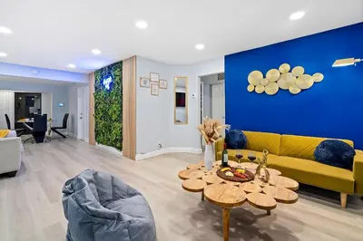 a living room with a yellow couch and a blue wall at Las Olas Fort Lauderdale Getaway Pool, BBQ, Mini Golf & Game Room in Fort Lauderdale