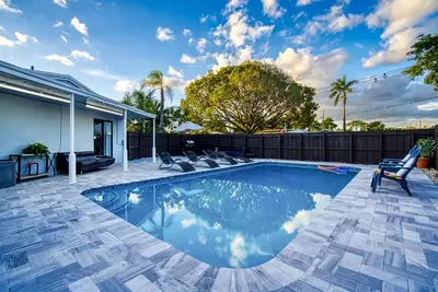 a swimming pool in a backyard with a fence at Las Olas Fort Lauderdale Getaway Pool, BBQ, Mini Golf & Game Room in Fort Lauderdale