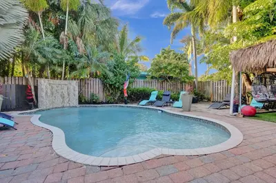 a swimming pool in a yard with chairs and trees at Kiki 4 - Men's Clothing optional Guest Houses in Fort Lauderdale
