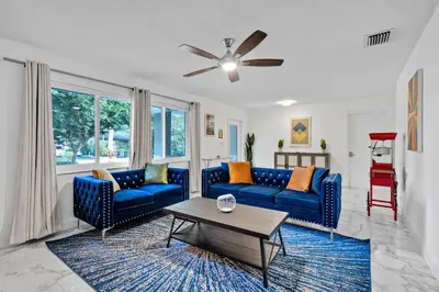 a living room with blue couches and a table at Waterfront House - Solar Heated Pool, Arcade Games in Fort Lauderdale