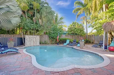 a swimming pool in a yard with chairs and a fence at Kiki 5 - Men's Clothing optional Guest Houses in Fort Lauderdale