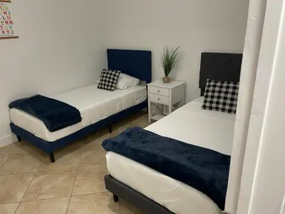 a room with two beds and a table with a plant at Relaxing Retreat 2BR Oasis with Pool and Outdoor BBQ in Pembroke Pines