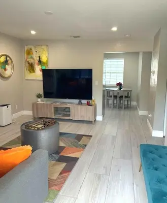 a living room with a large flat screen tv at Sunny Cottage in Fort Lauderdale