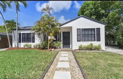 a white house with a palm tree at Sunny Cottage in Fort Lauderdale