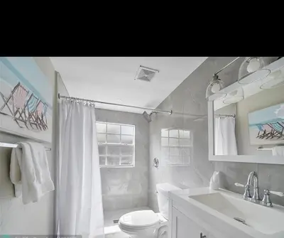 a white bathroom with a sink and a toilet at Sunny Cottage in Fort Lauderdale