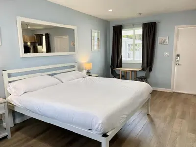 a bedroom with a large white bed and a mirror at Serene Studio W Parking 10 min from Beach and FLL in Hollywood