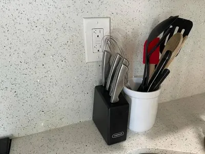 a cup of utensils is next to an electrical outlet at Serene Studio W Parking 10 min from Beach and FLL in Hollywood