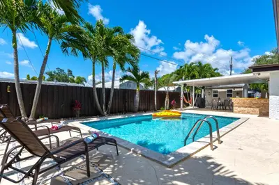 a swimming pool with two chairs and palm trees at Tropical house Miami in Cutler Bay