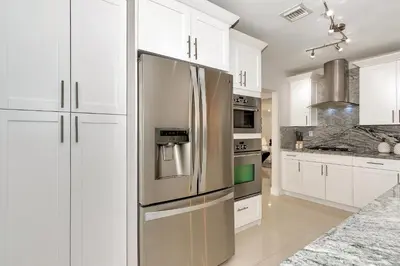 a kitchen with white cabinets and a stainless steel refrigerator at Tropical house Miami in Cutler Bay