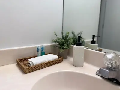 a bathroom sink with a mirror and a basket of towels at 1 SPRING PROMO - Sunny Isles Seaview Condo, Walk to Beach, Amazing Amenities in Sunny Isles Beach