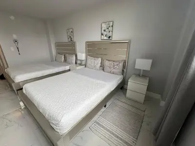 two beds in a small room with a lamp at Spacious Apt Ocean Reserve Resort Amenities in Sunny Isles Beach