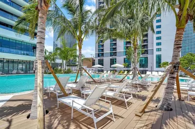 a row of chairs and palm trees next to a swimming pool at Great Studio Pool Gym & Views in Miami