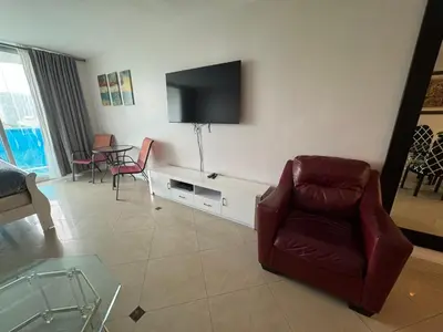 a living room with a chair and a tv on the wall at Luxury Ocean Reserve Condo Pool, Gym & Beach Access in Sunny Isles Beach