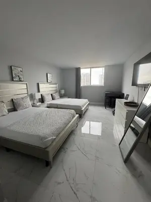 a bedroom with two beds and a desk and a television at Luxury Ocean Reserve Condo Pool, Gym & Beach Access in Sunny Isles Beach