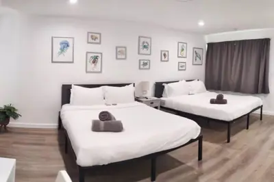 two beds in a hotel room with white sheets at Charming DBL W pool and parking 15 min to FLL and Beach in Hollywood