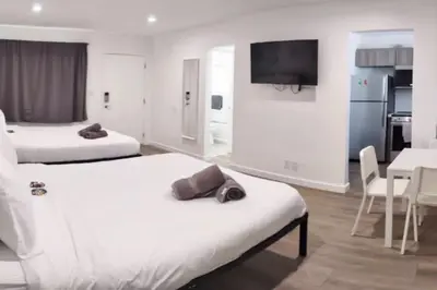 a hotel room with two beds and a table and a tv at Charming DBL W pool and parking 15 min to FLL and Beach in Hollywood