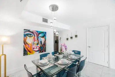 a dining room with a table and a painting on the wall at Exclusivity & Relaxation Offered By Our Condo in Miami