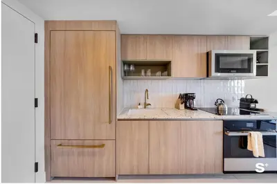 a kitchen with wooden cabinets and a sink and a microwave at Downtown 1-BD Condo with City Views in Miami