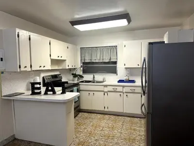 a kitchen with white cabinets and a black refrigerator at Bed in 6-Bed Dormitory Room in Miami
