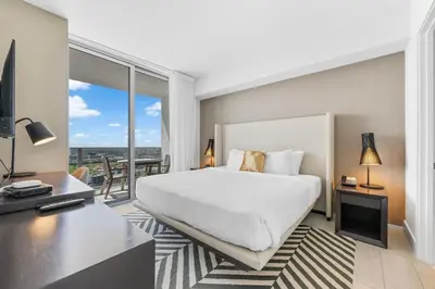 a hotel room with a bed and a desk and a balcony at Stunning High-Floor City View 1BR Hyde Beach House in Hollywood