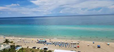 a beach with chairs and people in the water at Beautiful Hyde Resort Luxe 2BR Private Beachfront in Hollywood