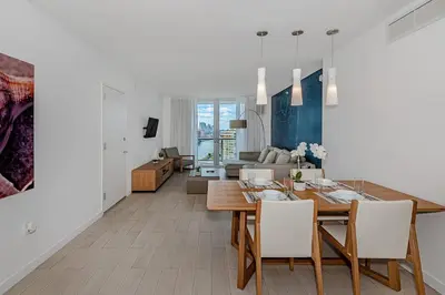 a dining room and living room with a table and chairs at 1 Bedroom & Kitchen at Beachwalk Luxe Pool - Gym in Hallandale Beach
